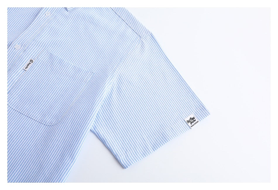 Partial front view of a white shirt with fine blue stripes, a chest pocket, buttons, and short sleeve.