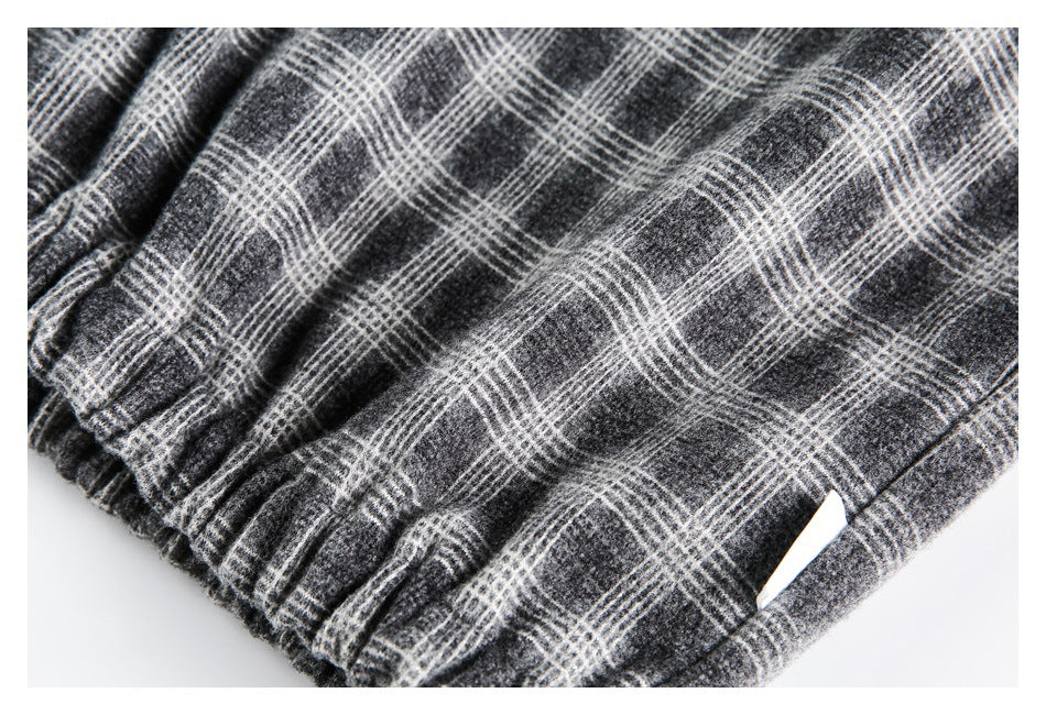 Close-up of gathered elastic edging and a small opening in charcoal gray plaid fabric.