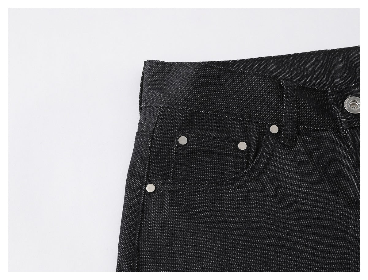 Close-up of black textured pants showing the waistband, front pocket, coin pocket and silver rivets.