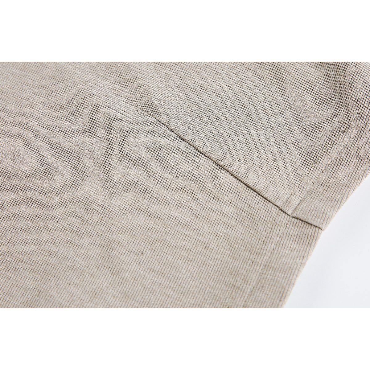 Close-up of beige shirt fabric with a diagonal stitched seam and intersecting panel seam.