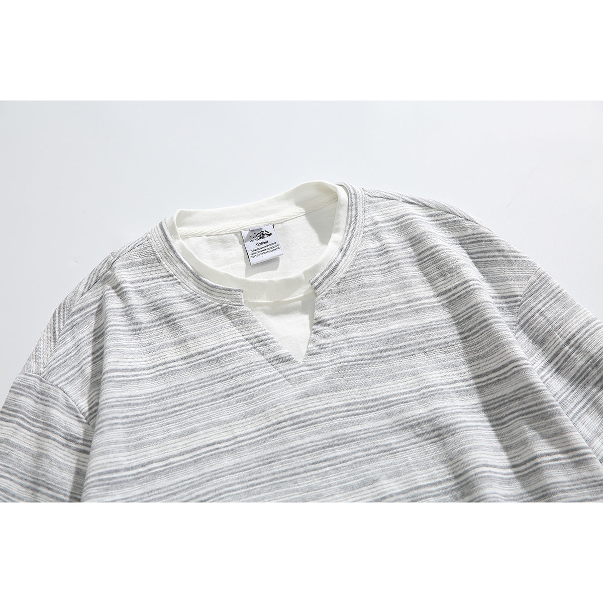 Close-up of a gray-and-white striped shirt with a split V-neck and white inner layer.
