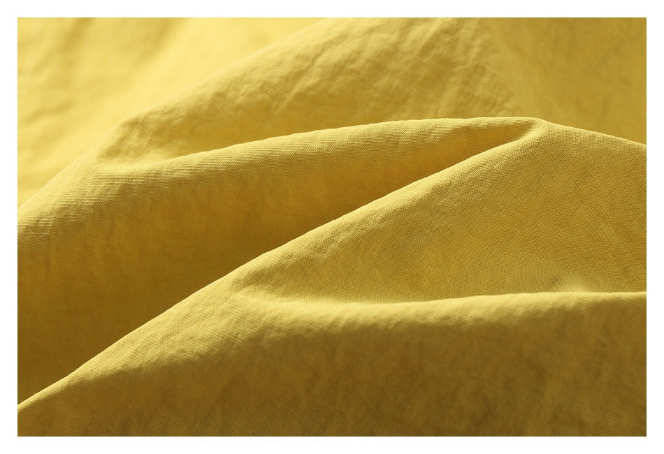 Mustard-yellow fabric in soft folds, with a fine woven texture visible.