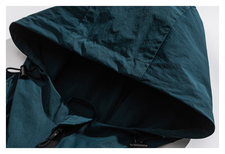 Close-up of a dark teal hood with black drawcords and adjusters.