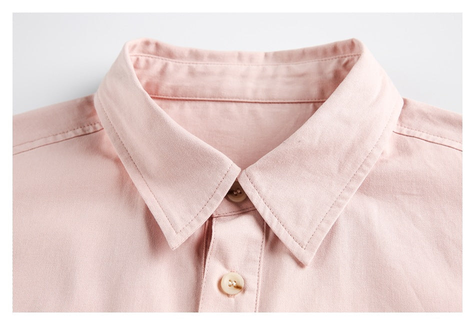 Close-up of a pale pink shirt collar, top button, and front placket.