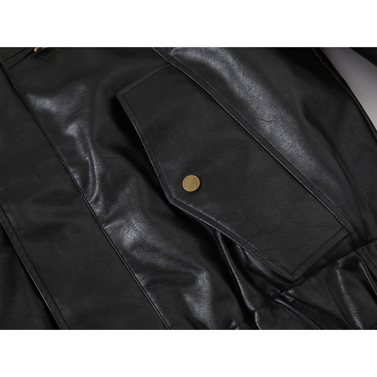 Close-up of a black jacket's flap pocket with a round brass-tone snap and stitched edges.