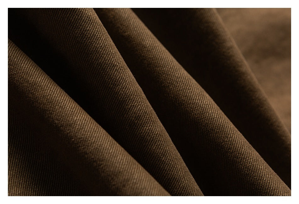Macro view of dark brown fabric draped in folds, showing its diagonal weave.