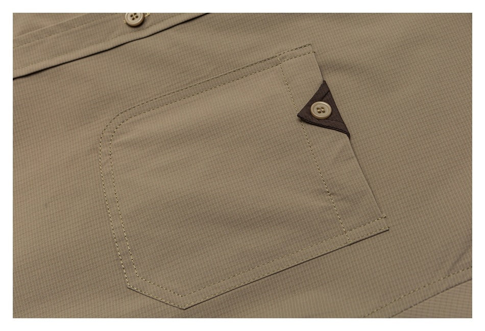 Close-up of a taupe garment's stitched pocket with a triangular button tab.