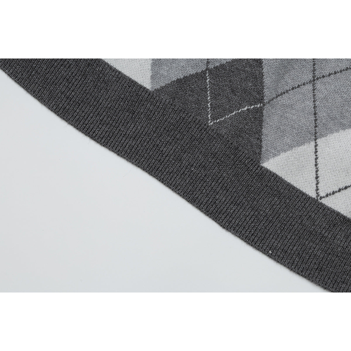 Close-up of the gray argyle polo's dark ribbed hem and diamond pattern.