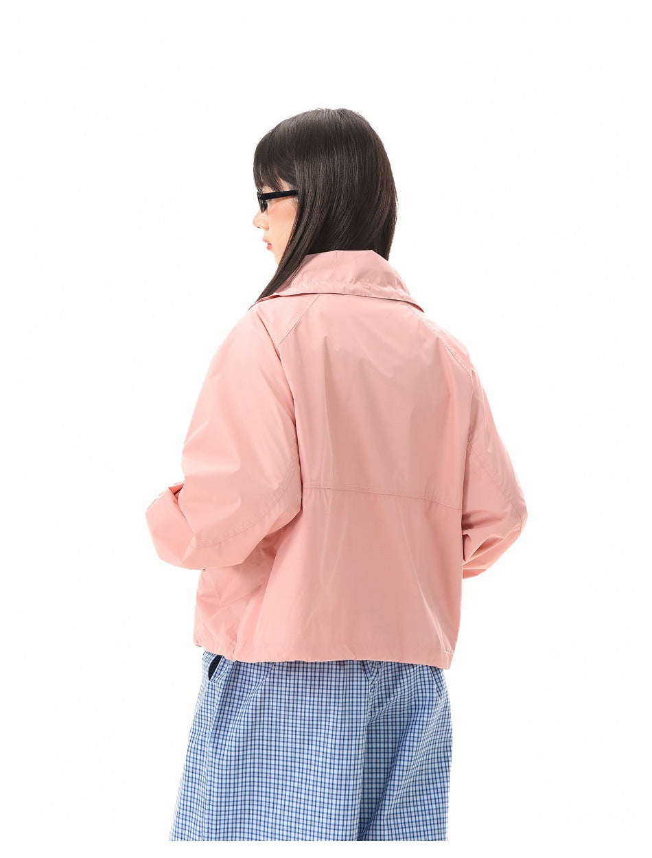 Rear view of a model wearing a pale pink jacket with a raised collar and wide blue checked trousers.