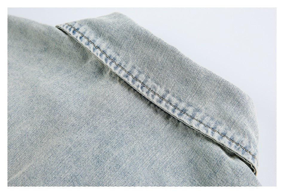Close-up of light-wash denim with a curved, tan-stitched seam.
