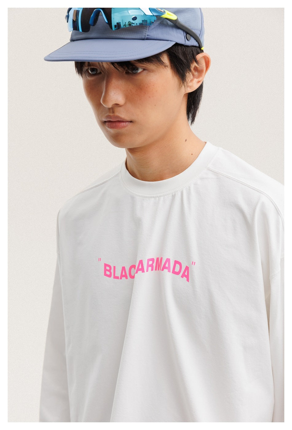 Close-up of a model wearing a white long-sleeve shirt with pink BLACKARMADA lettering across the chest.