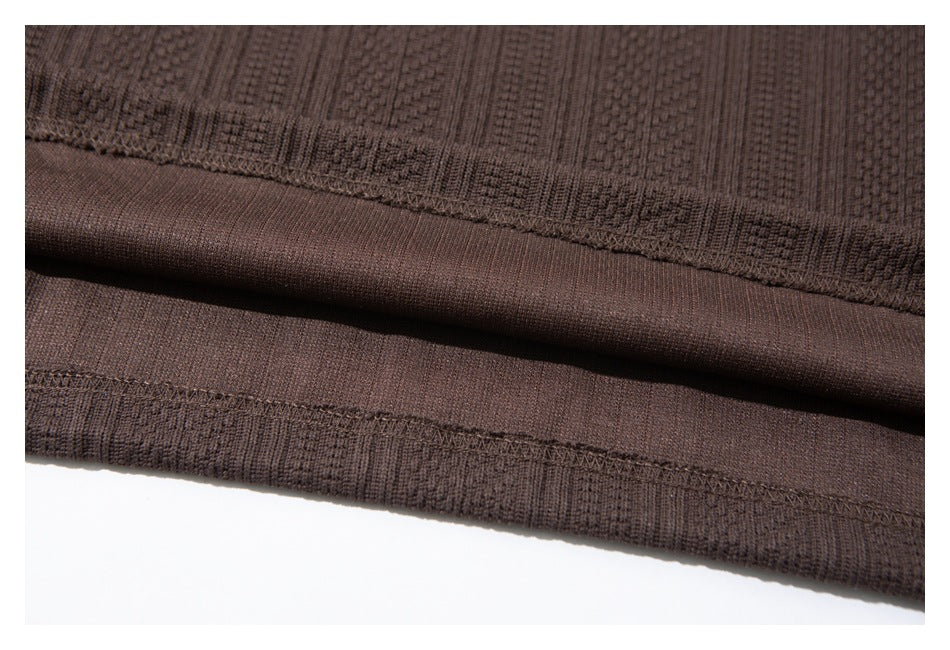 Close-up of a dark brown garment hem showing textured fabric and stitched seams.