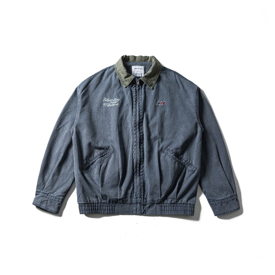 Navy blue washed zip-front jacket with olive green collar, slanted pockets, elastic hem and chest embroidery, flat lay