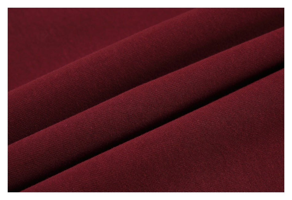 Close-up of burgundy fabric arranged in diagonal folds, showing its fine knit texture.