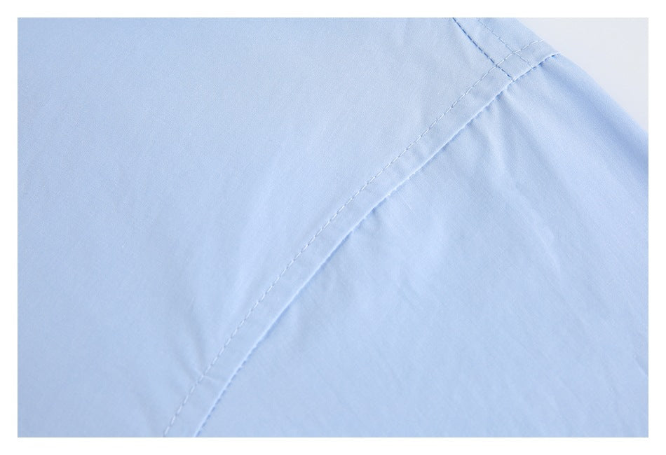 Close-up of stitching along a curved seam on light blue shirt fabric.