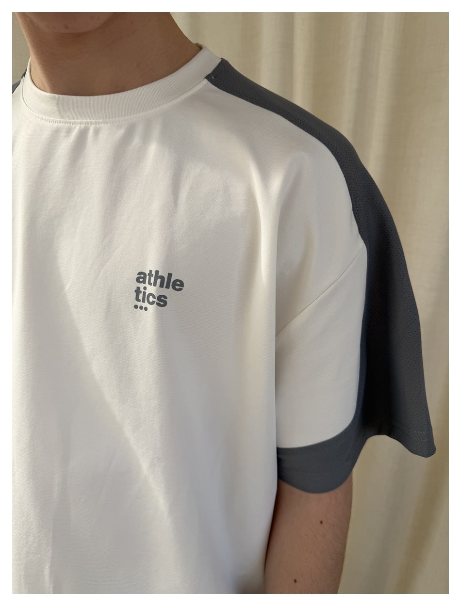 Close-up of a white T-shirt with a charcoal-gray mesh shoulder and sleeve panel and small chest lettering.