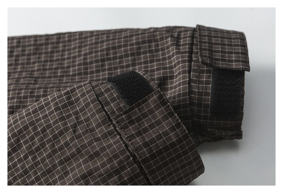 Close-up of dark brown checked garment cuff with a black hook-and-loop adjustment tab.