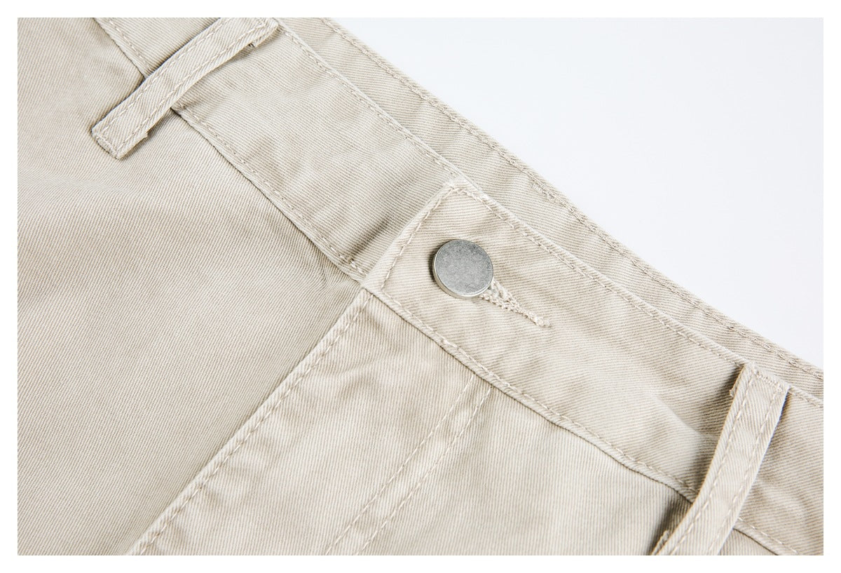 Close-up of light beige trouser waistband with a metal button, belt loop, and double-stitched seams.