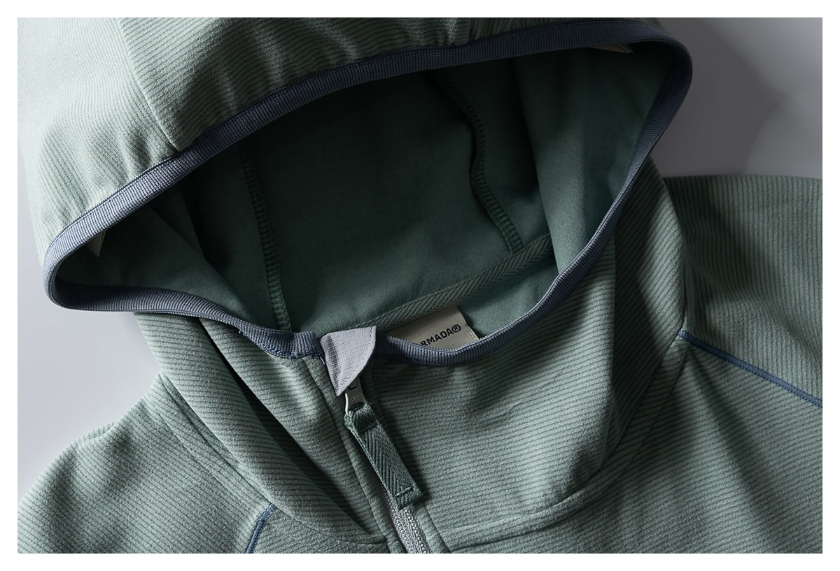 Close-up of the sage-green jacket’s hood, dark edge trim, zipper, and interior neck label.