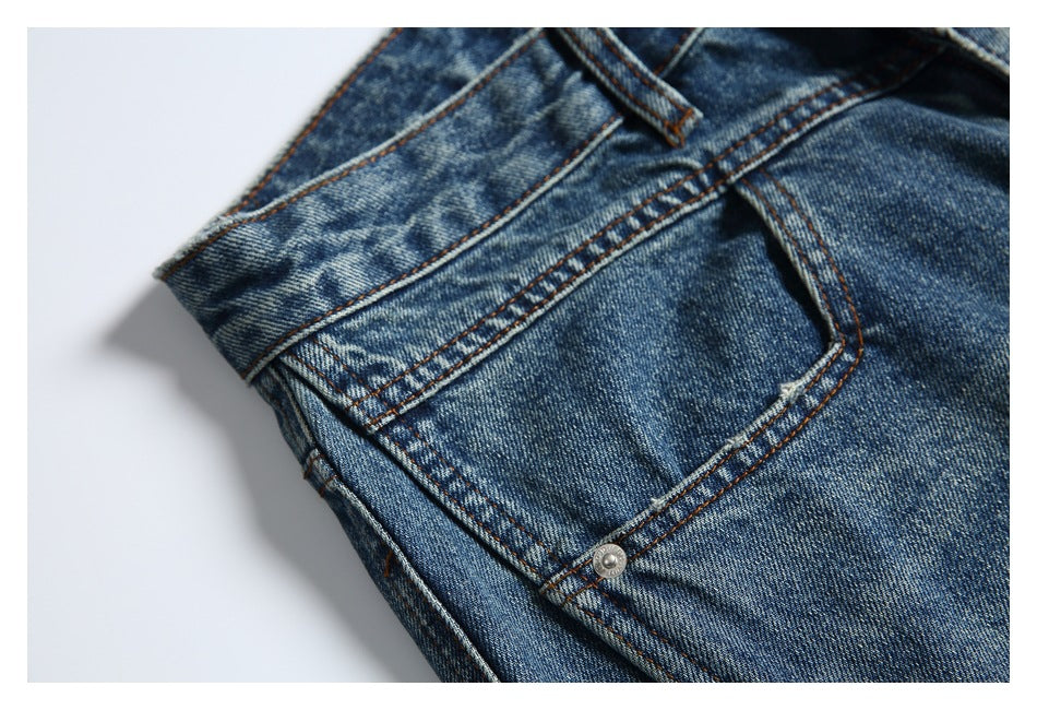 Close-up of a blue-wash jeans pocket with orange stitching and a small metal rivet.