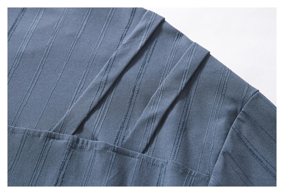 Close-up of the blue-gray top's shoulder and sleeve seam with a raised vertical stripe pattern.
