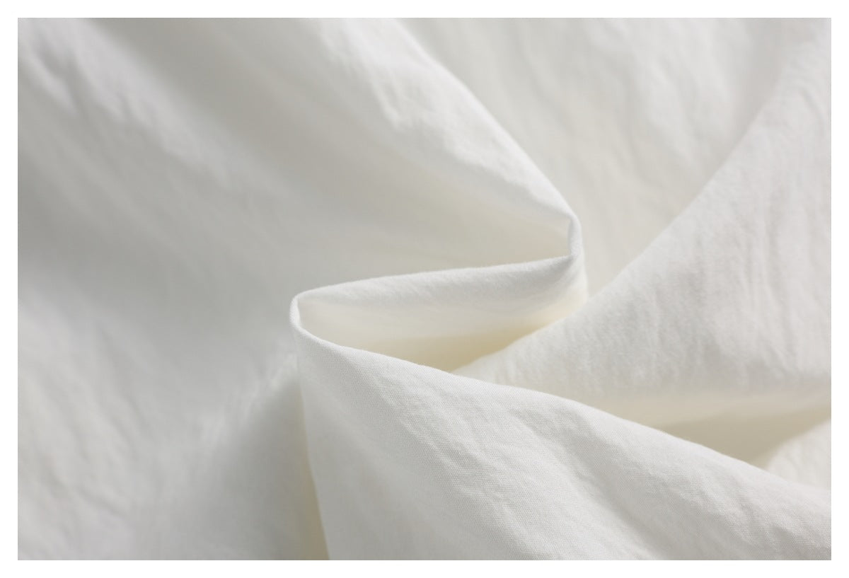 Close-up showing the softly folded white garment fabric and its surface texture.