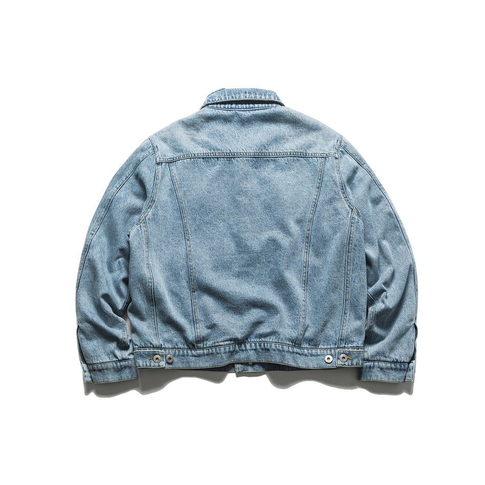 Back view of a light blue denim jacket laid flat, showing its panel seams and adjustable buttoned hem.