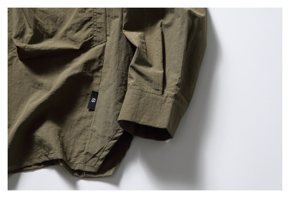 Close-up of the olive-brown shirt's wide sleeve cuff and small black side tab.
