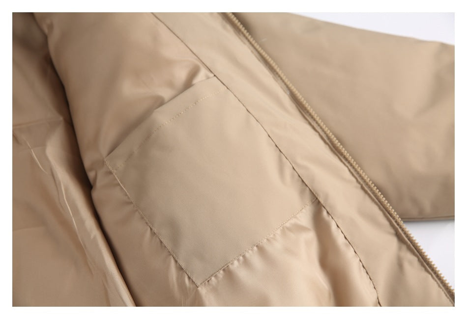 Close-up of a tan garment with a zipper and a rectangular stitched patch pocket.