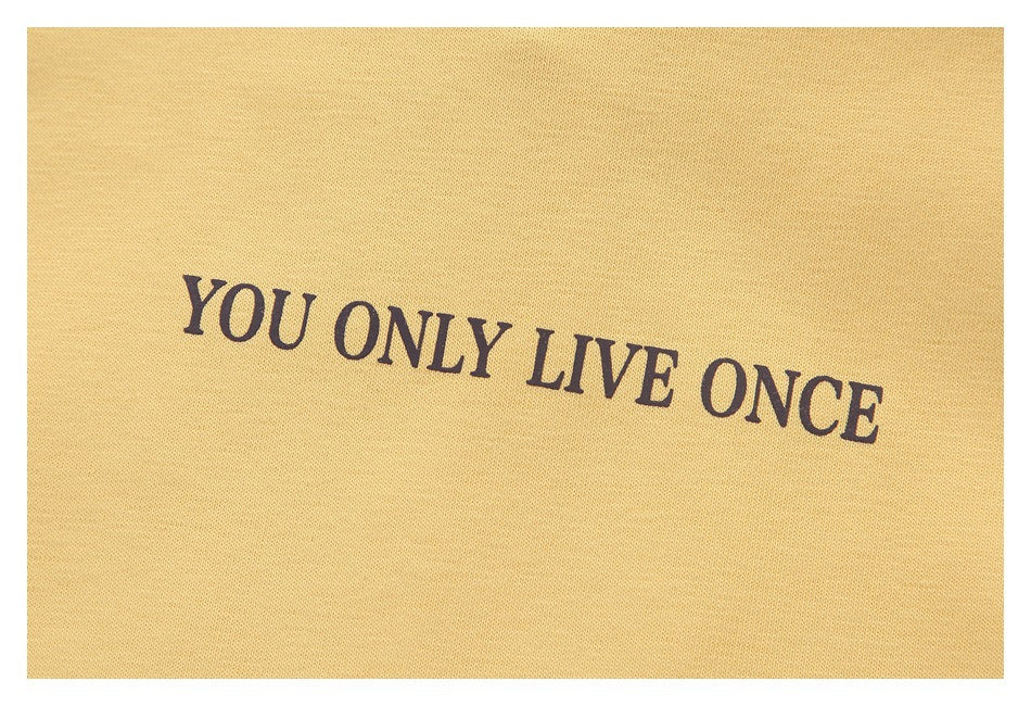 Close-up of dark “YOU ONLY LIVE ONCE” lettering printed on pale yellow fabric.