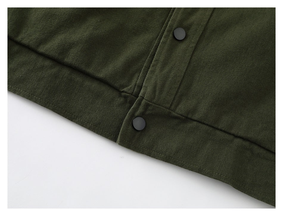 Close-up of the olive jacket hem, front placket, and two black snap fasteners.