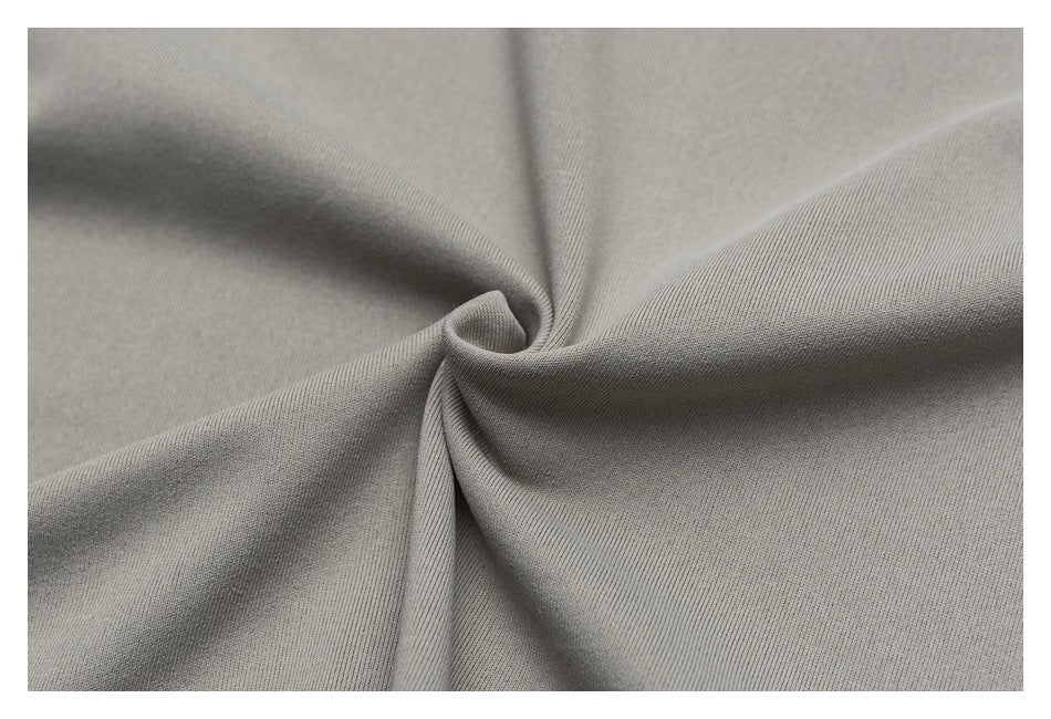 Close-up of light gray fabric gathered into soft folds, showing its fine surface texture.