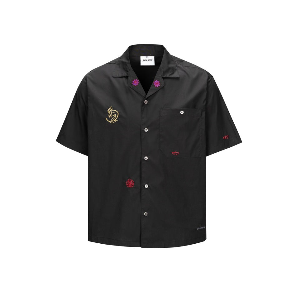 Black short-sleeve camp collar shirt with chest pocket and colorful embroidered motifs, front view