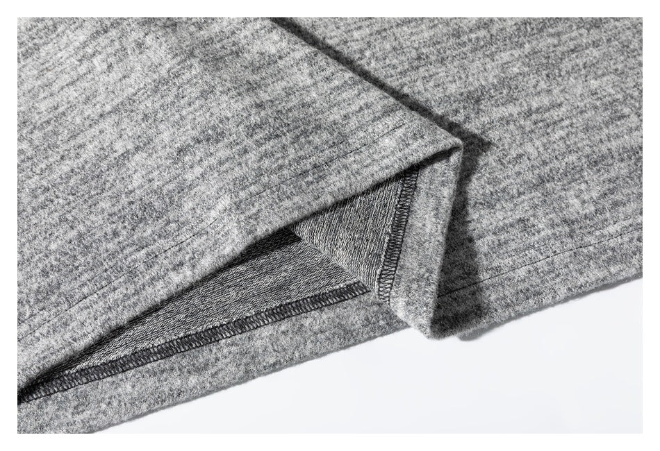 Close-up of the gray marled shirt's folded hem and visible overlock stitching.