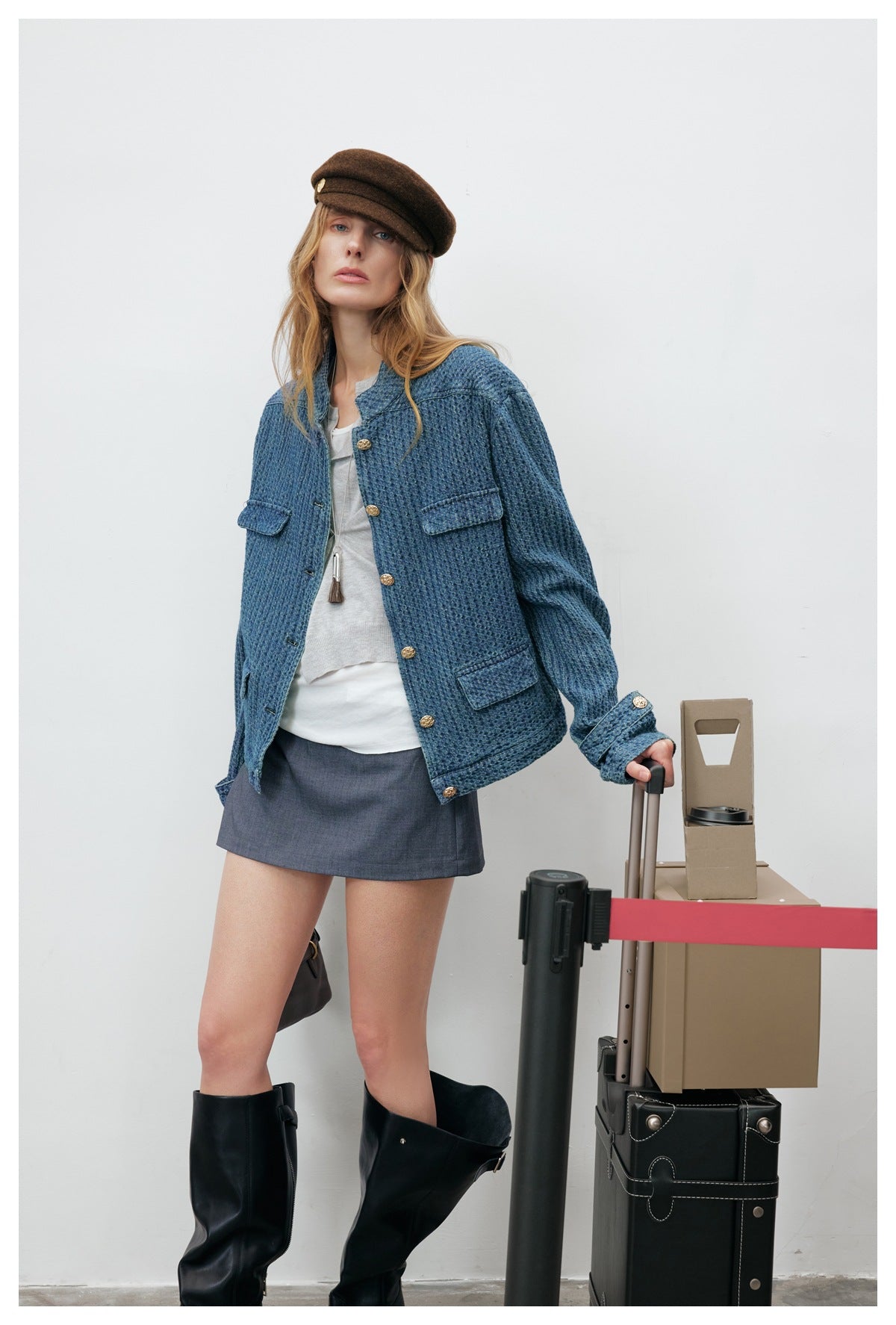 Model wearing a blue textured jacket with gold buttons over a white top and gray mini skirt.