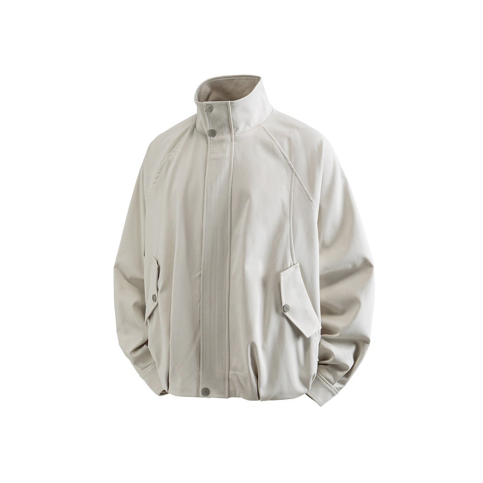 Beige stand-collar jacket in three-quarter view showing raglan sleeves, snap flap pockets and ribbed-looking hem