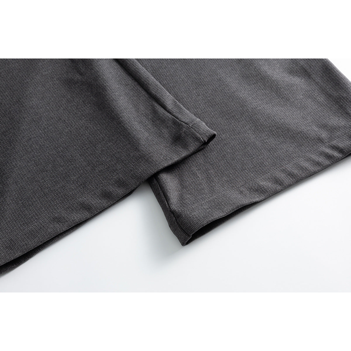 Close-up of the hems and drape of charcoal gray wide-leg trousers.