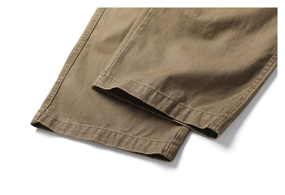 Close-up of the straight hems of khaki-brown trousers on a white background.
