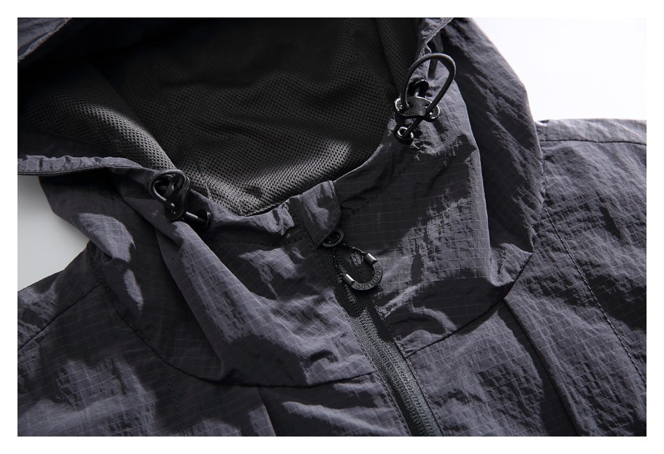 Close-up of a charcoal hooded jacket showing mesh lining, drawcord toggles, and the front zipper.