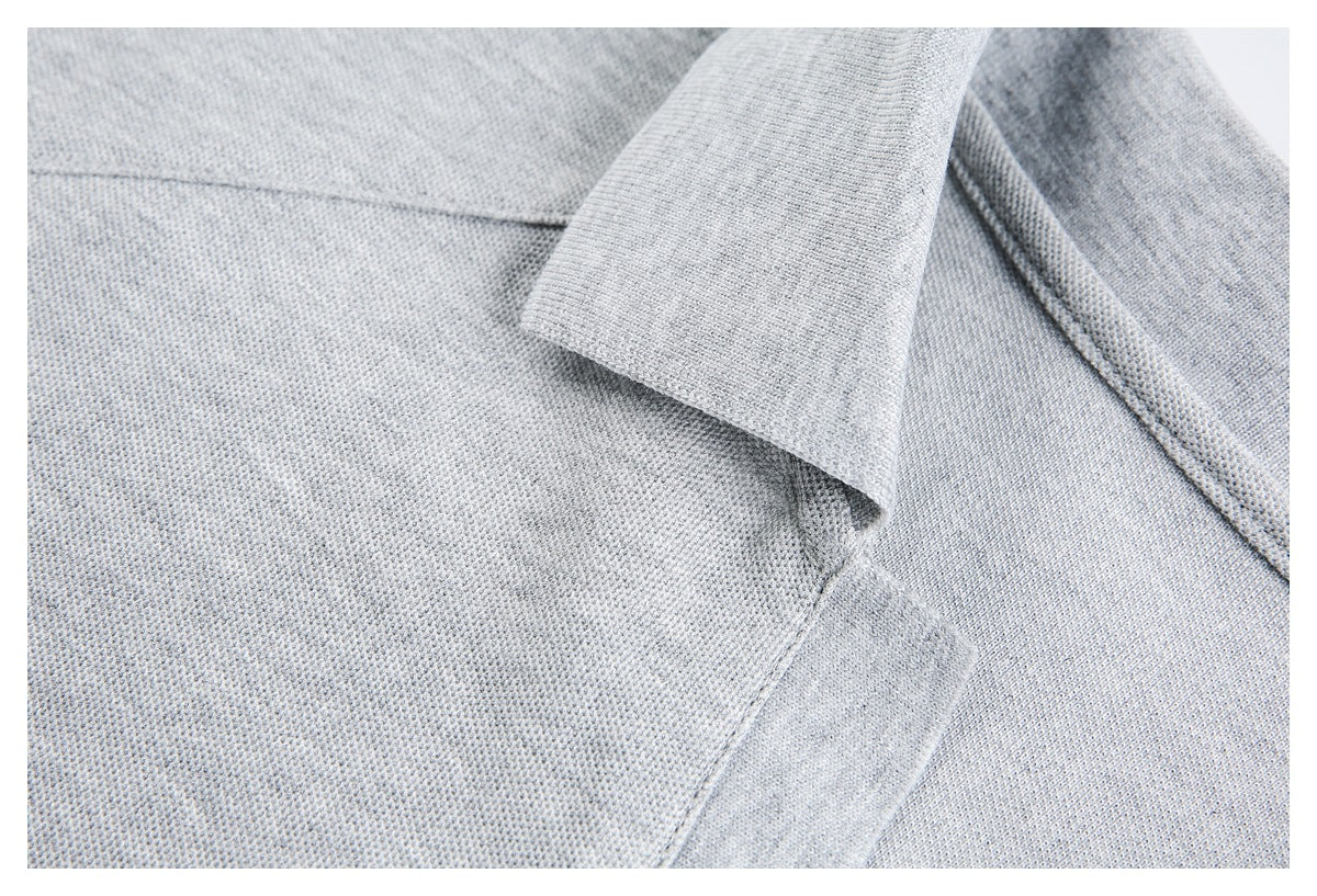 Close-up of a light gray polo shirt collar, shoulder seam, and textured fabric.