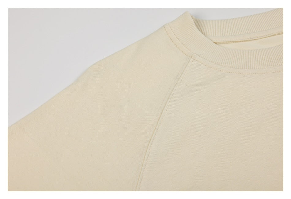 Close-up of an ivory sweatshirt’s ribbed crew neck and raglan sleeve seam.