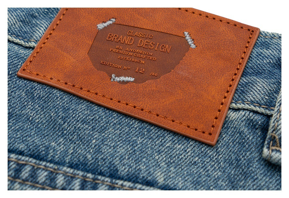 Close-up of a brown leather-look patch sewn onto blue jeans, embossed with English lettering.