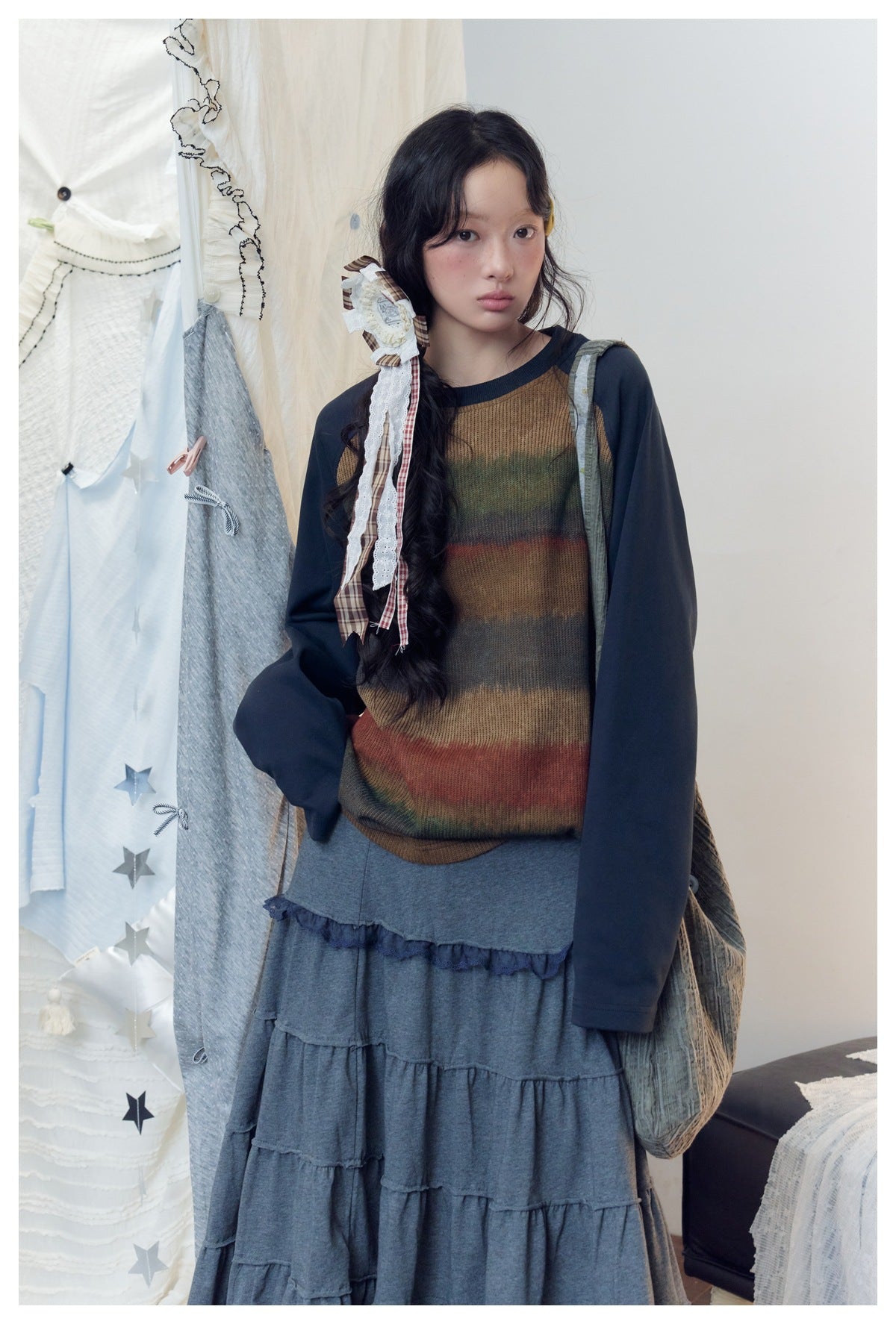 Closer view of a model in a brown multicolor striped top with navy sleeves and a gray tiered skirt.