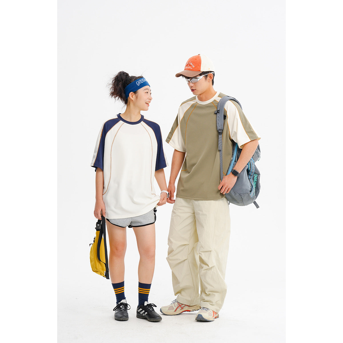 Two models wear color-block raglan T-shirts: one white with navy sleeves and one olive with cream sleeves.