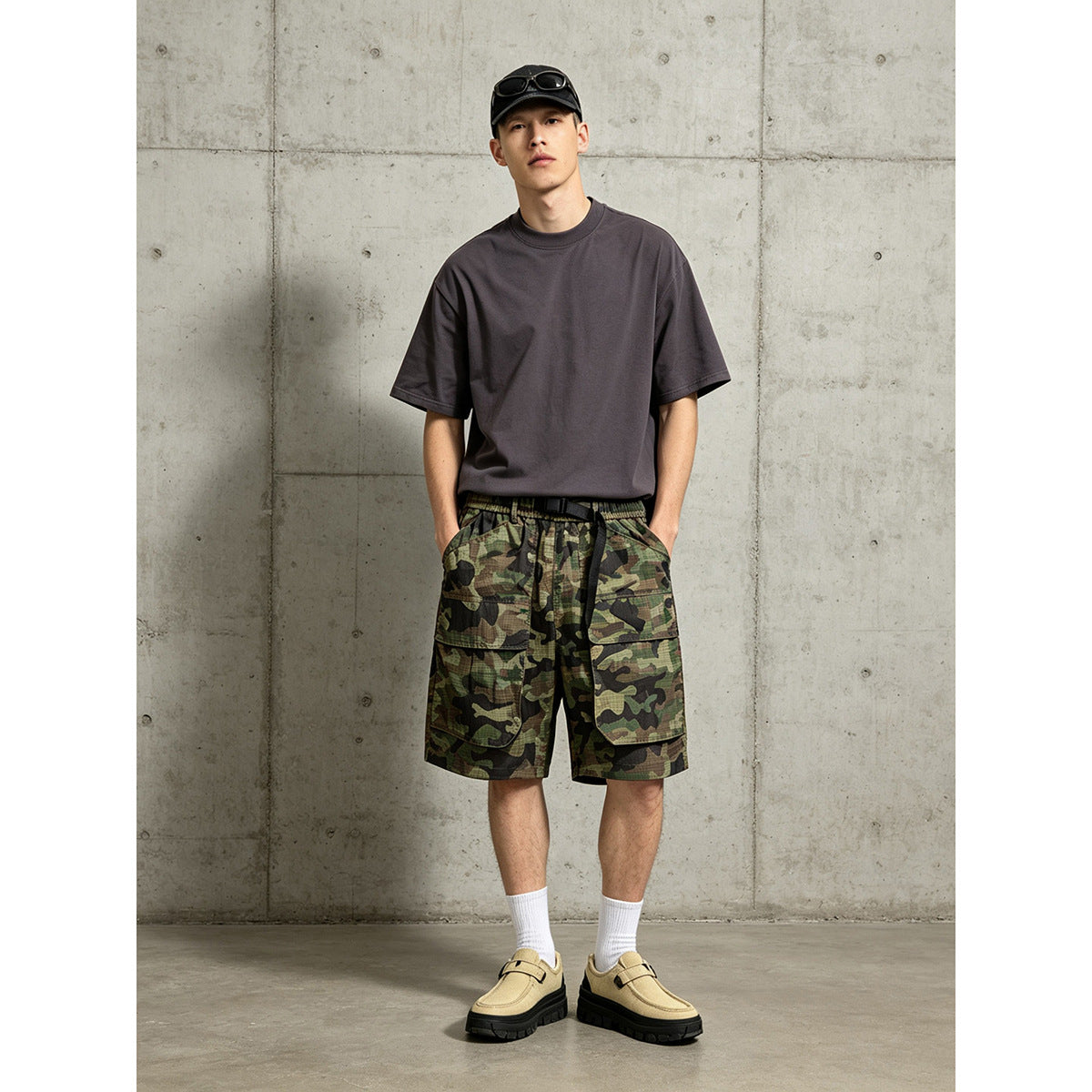 Model wearing olive, brown and black camouflage cargo shorts with a black belt and a charcoal T-shirt.