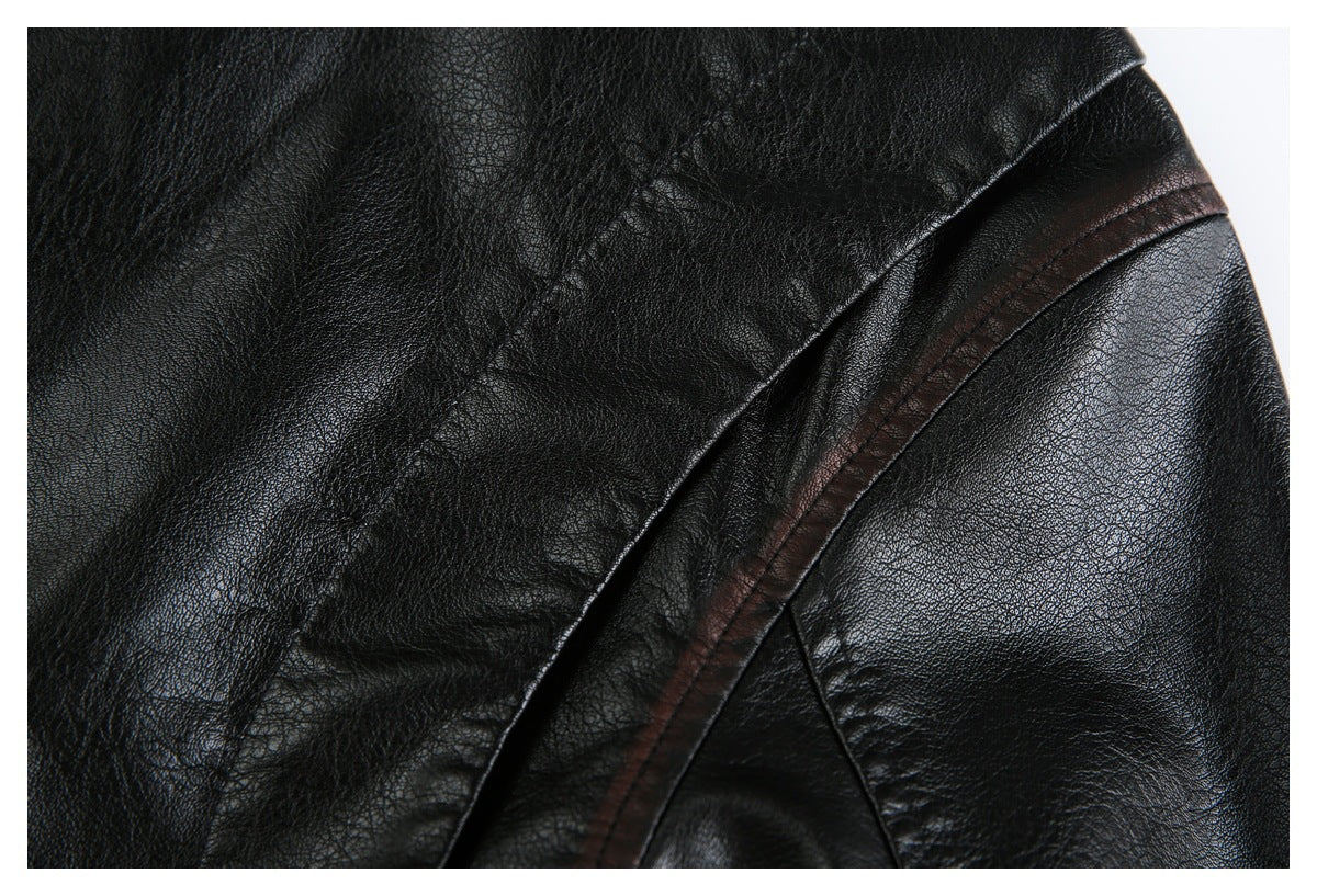 Close-up of a black leather-look jacket shoulder seam with dark brown trim.