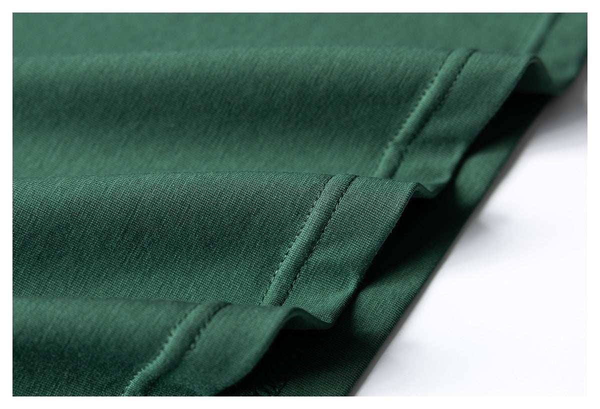 Close-up of dark green garment fabric with folded edges and stitched seams.
