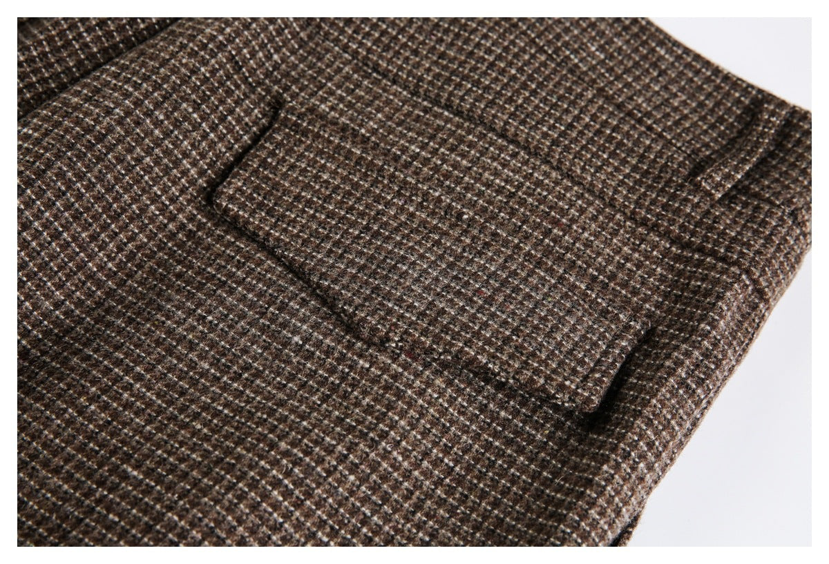 Close-up of brown small-check fabric with a single rectangular flap pocket and stitched edges.