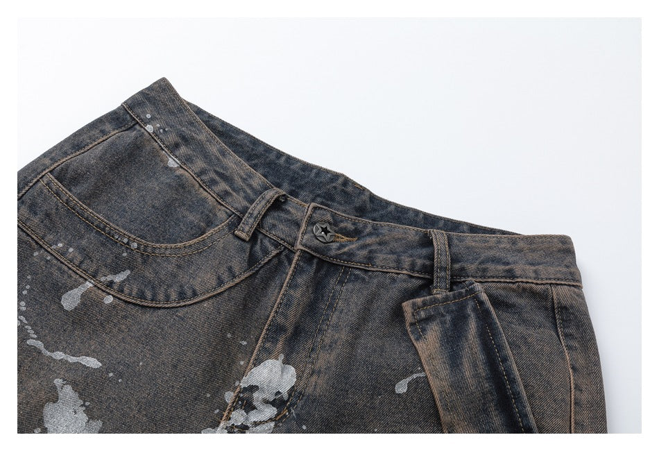 Close-up of the charcoal-gray splatter-print jeans waistband, button, belt loops, and front pockets.