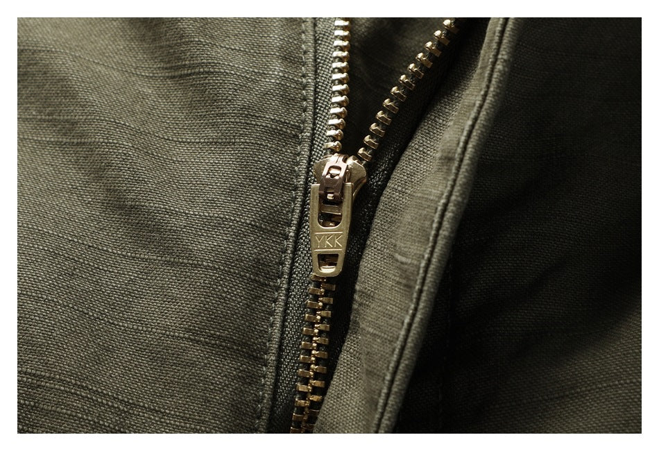Close-up of a brass-colored YKK zipper against olive pants fabric.